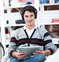 Picture of a man holding a tablet and wearing headphones
