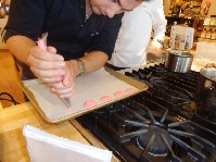 Baker squeezing dollops of pink cookie dough on a cookie sheet