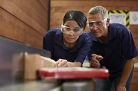 Experienced worker helping Apprentice in machine shop
