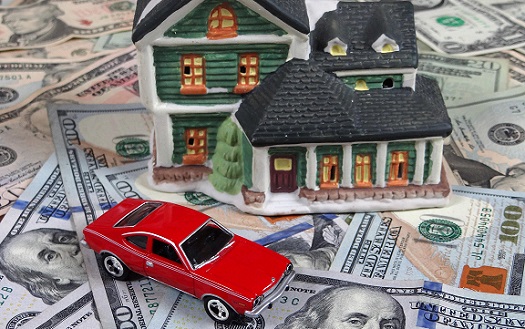 Miniature house and car on top of hundred dollar bills