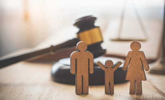 Figures representing a family in front of a gavel and scales of justice.