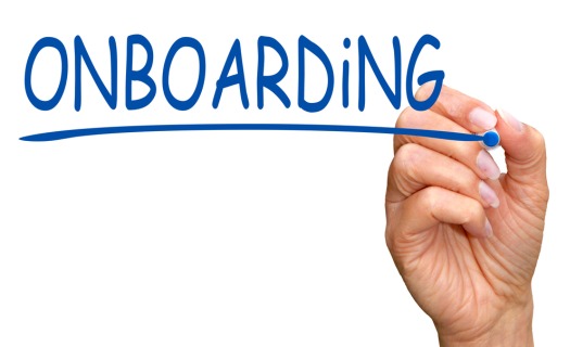 Woman's hand writing ONBOARDING on a whiteboard. 