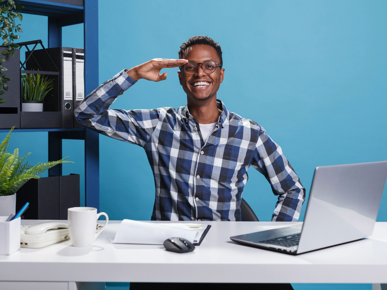 Veteran entrepreneur at desk with laptop who is saluting