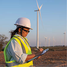 women engineer working and holding the report at wind turbine farm Power Generator Station on mountain,Thailand people