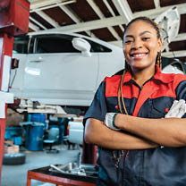 Engineer team checking under car condition on lifter in garage.Young auto mechanic in uniform is looking at camera and smiling examining car. 